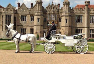 White Glass Fronted Landau with a Pair of White Horses outside stately home with roof down White Glass Fronted Landau with a Pair of White Horses outside stately home with roof down